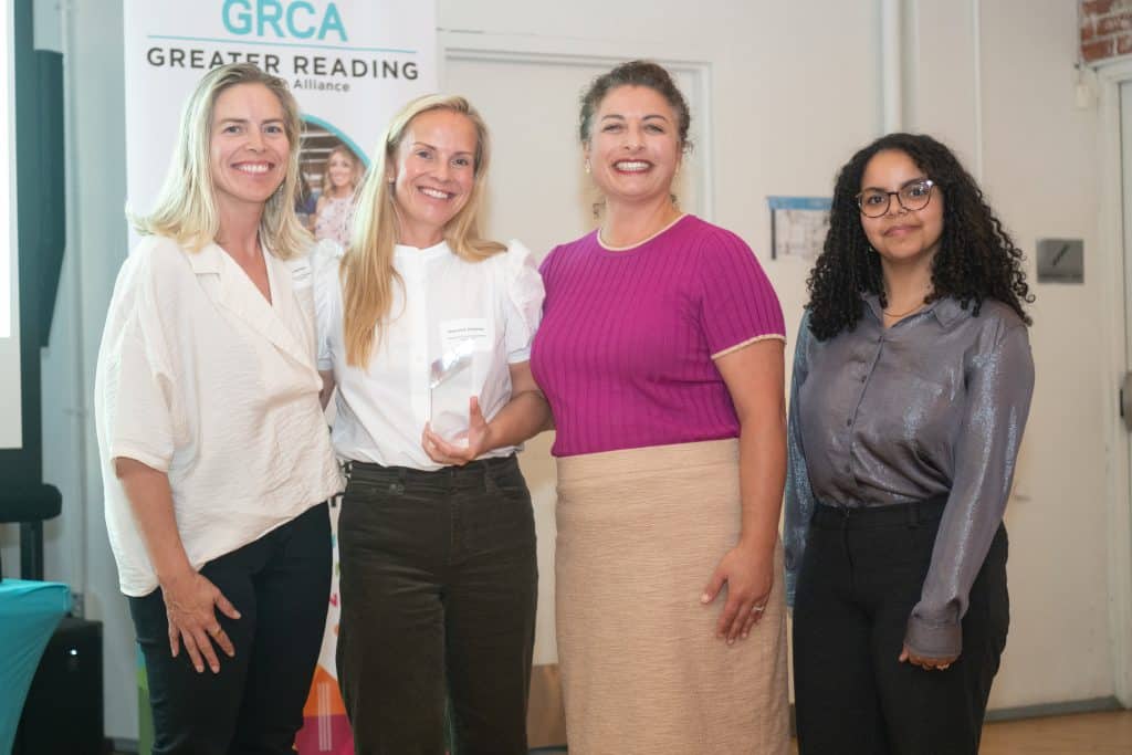 four women standing and posing with an award