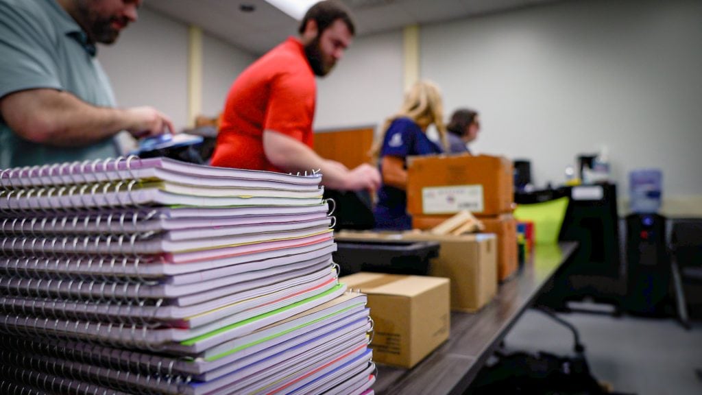 ACECO Volunteers forming an assembly line to pack essential school supplies into backpack donations